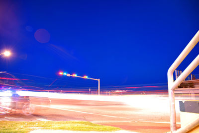 Illuminated street against blue sky at night