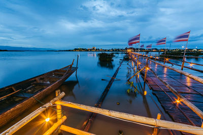 Illuminated pier on lake against sky