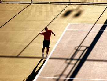 Full length of tennis player serving in court