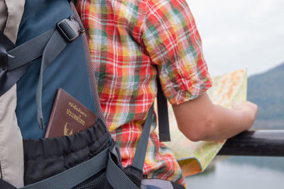 Midsection of person wearing backpack with passport