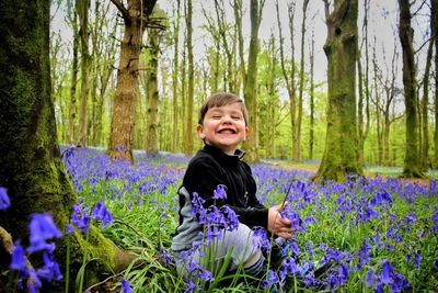 Portrait of smiling girl holding flowers in forest