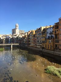 River by buildings against clear sky