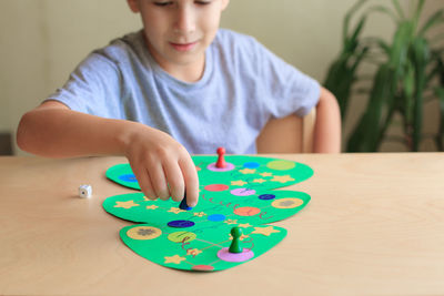 Child rolls the dice and moves the chip across the christmas playing field.