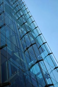 Low angle view of glass building against clear blue sky