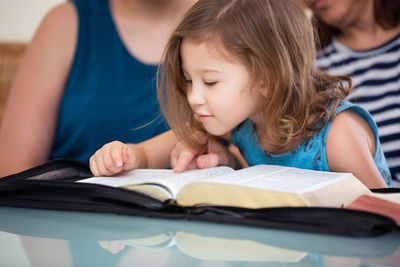 Midsection of woman reading book on table