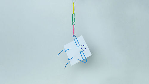 Close-up of paper clips hanging against white background