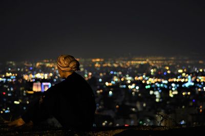 Young man standing against illuminated city at night