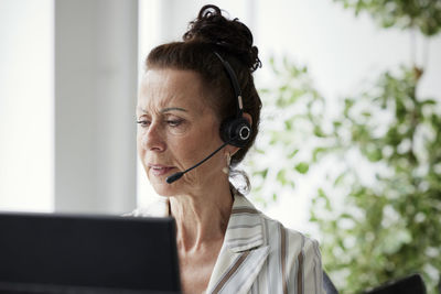 Woman wearing headset using desktop pc in office