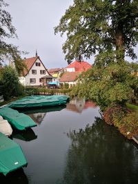 Houses by lake and buildings against sky