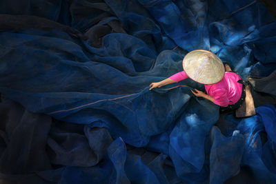 Woman sew the fishnet. fisherman repairs fishing net. needle with hand repairing net in home.