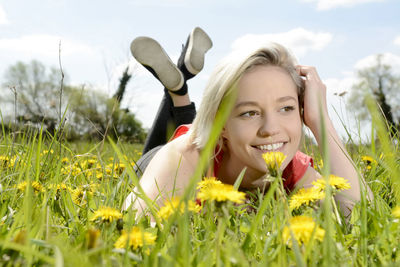 Smiling young woman looking away while lying on grass