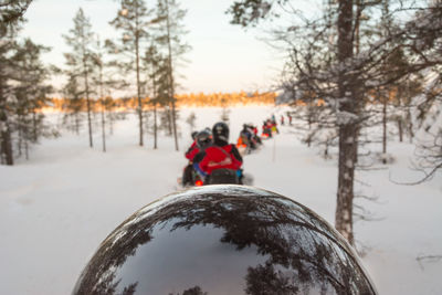 Rear view of people on snow covered field against sky