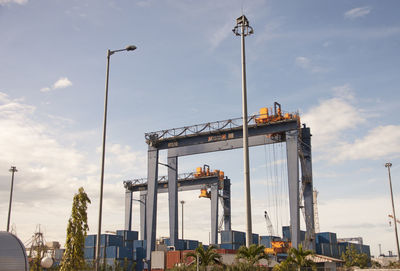 Low angle view of cranes against sky in city