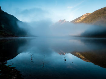 Scenic view of lake by mountains against sky