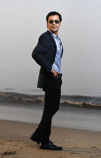 Young businessman standing at beach