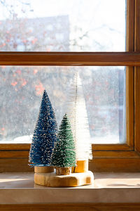 Colourful christmas trees on the window. trendy home decor for winter holidays.