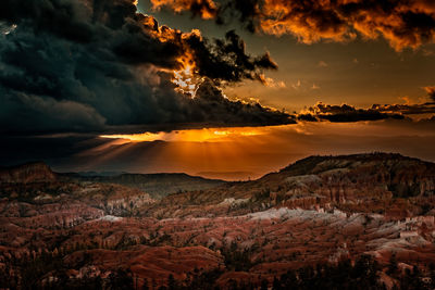 Scenic view of mountains against dramatic sky during sunset