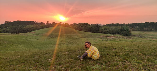 Portrait of women sitting on field against sky during sunset