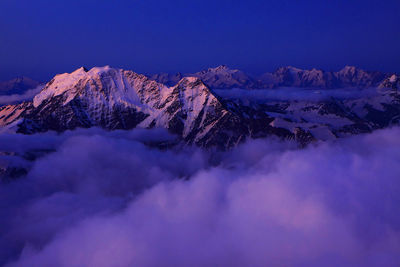 Scenic view of snowcapped mountains covered with cloudscape at dusk