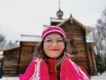 Portrait of smiling woman against built structure during winter