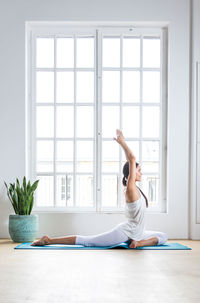 Full length of young woman exercising at home