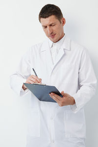 Doctor holding stethoscope against white background