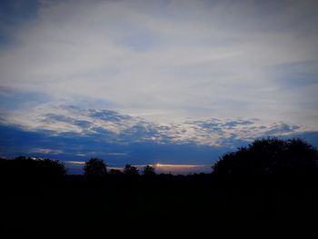 Silhouette trees on landscape against sky during sunset