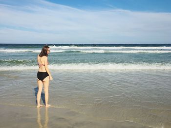 Rear view of young woman standing at beach