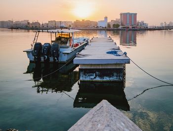 Boats moored in lake against sky during sunset