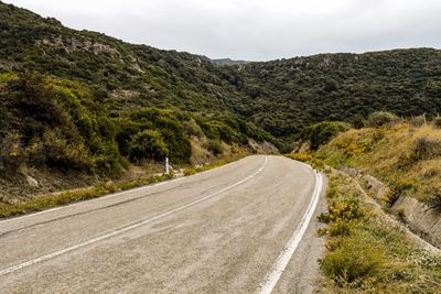 Road leading towards mountains against sky