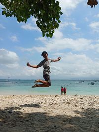 Friends enjoying at beach against sky