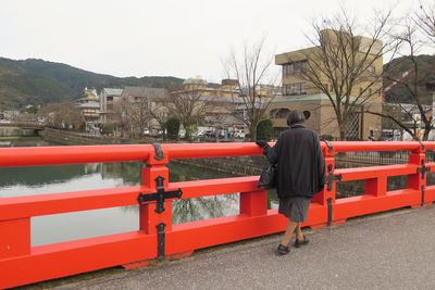 Rear view of men standing by railing against sky