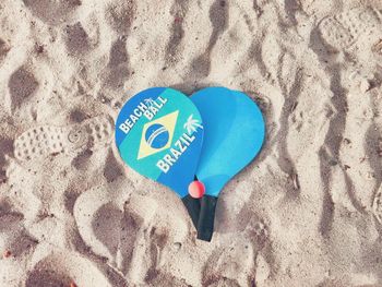 High angle view table tennis rackets at sandy beach