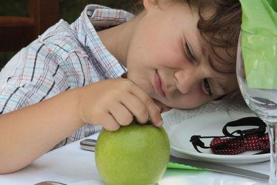 Cute boy with apple on table