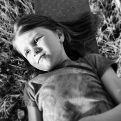 High angle view of girl looking away while lying on grass