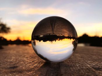 Close-up of crystal ball on landscape during sunset