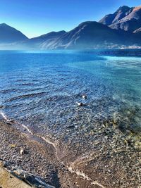 Scenic view of sea and mountains against blue sky