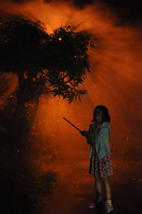 Man standing by tree at night