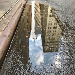 Reflection of buildings in puddle on street