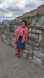 Portrait of smiling woman leaning on stone wall