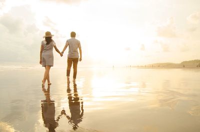 Rear view of couple walking on beach