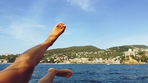 Low section of woman by sea against sky