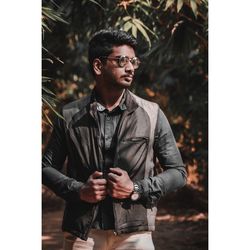 Young man looking away while standing outdoors