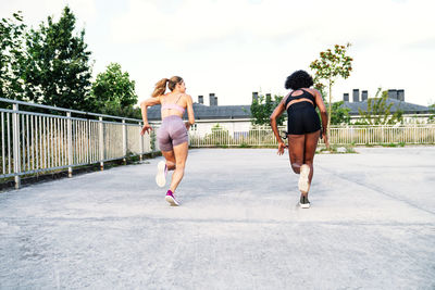 Sportive multiethnic females in activewear competing with each other while running fast together during training