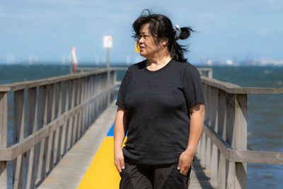 An asian middle aged woman on a jetty with a yellow carpet 
