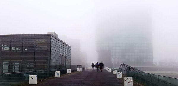 People walking on modern building in city against sky