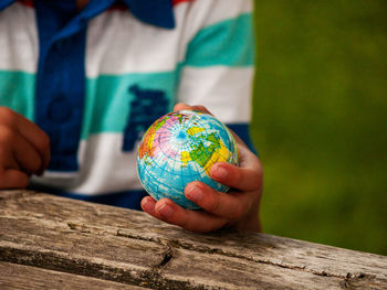 Midsection of boy holding globe on table