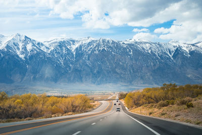 Road amidst snowcapped mountains against sky