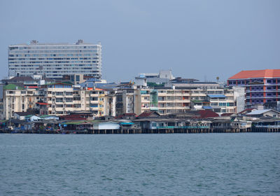 Buildings by sea against clear sky