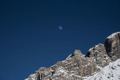 Low angle view of snowcapped mountain against blue sky